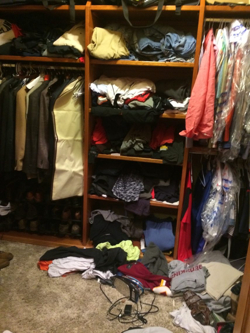 A messy closet that needs organizing. There are clothes all over the floor.