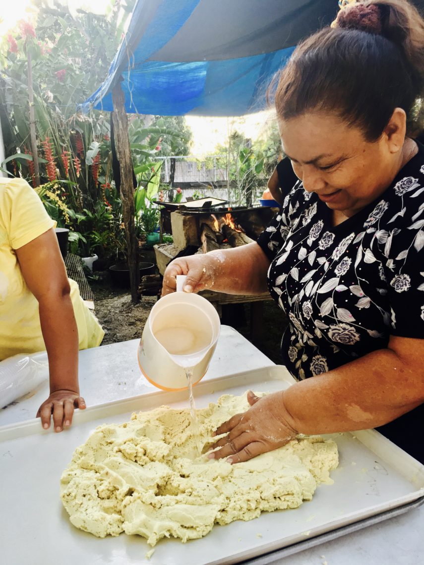 A woman kneads masa to make homemade tortillas in an outdoor kitchen 