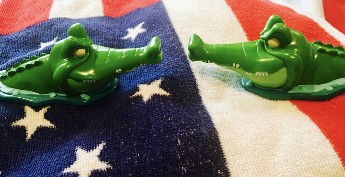 Two plastic alligators stare at each other on top of the american flag