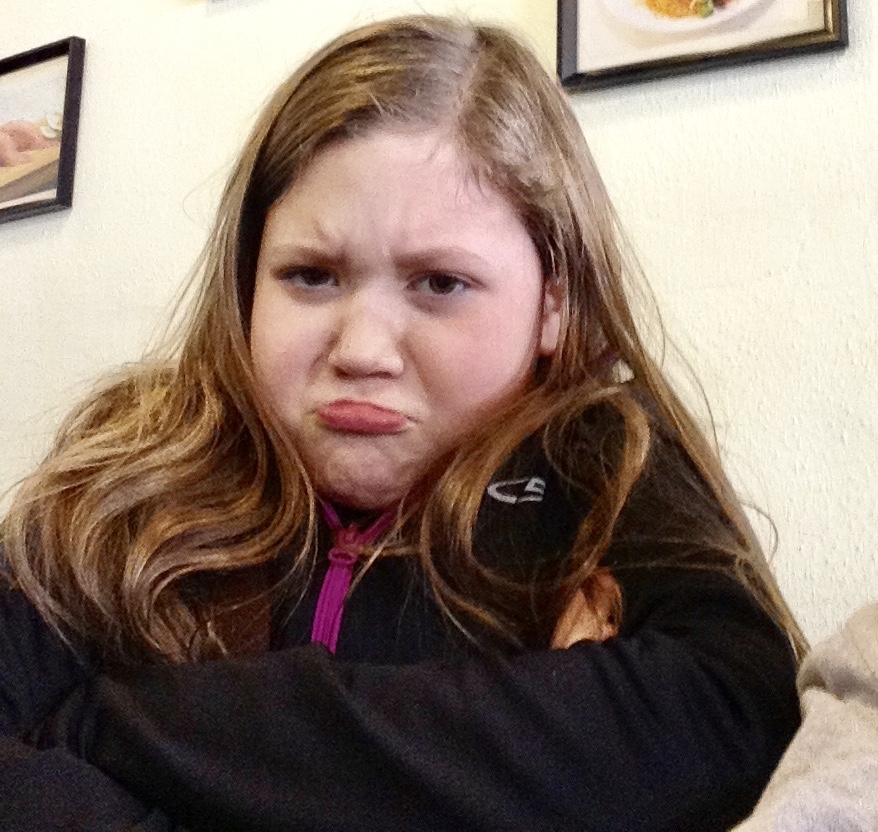 A little girl pouts and frowns at the camera.