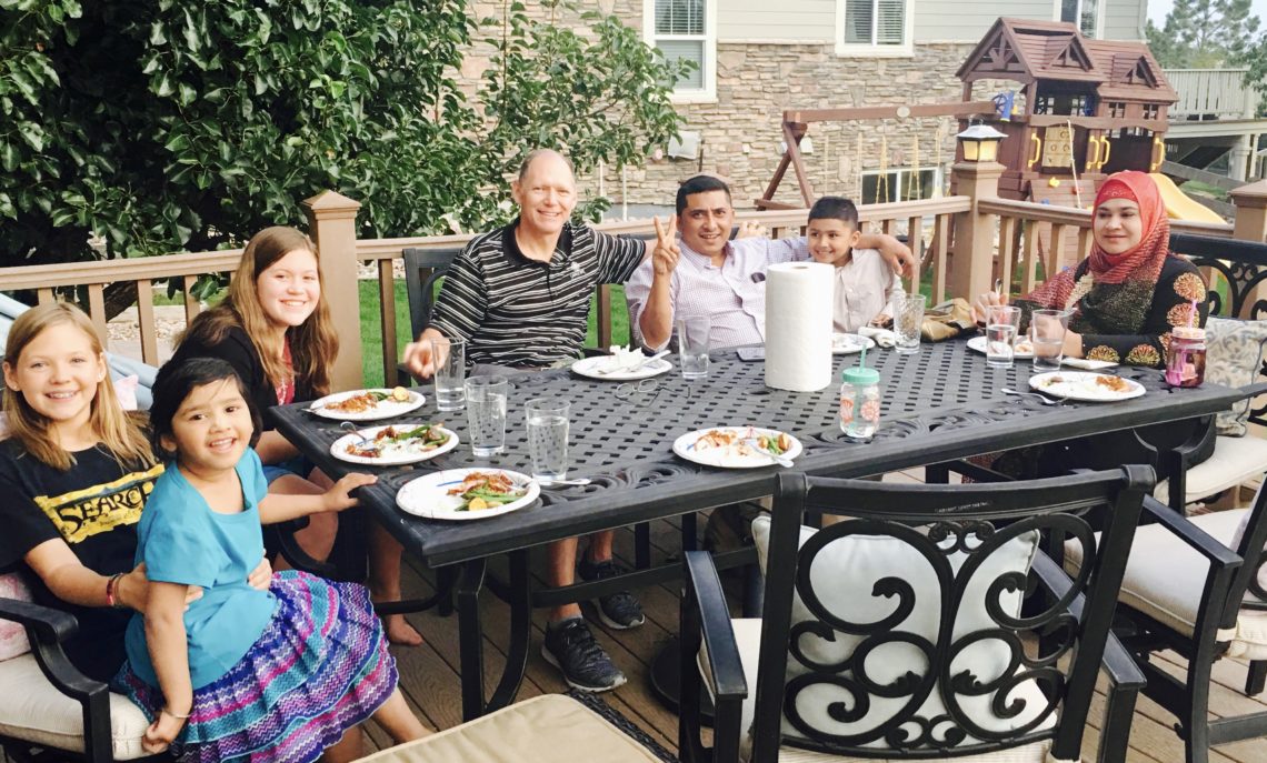 An American and Burmese Refugee family eats together
