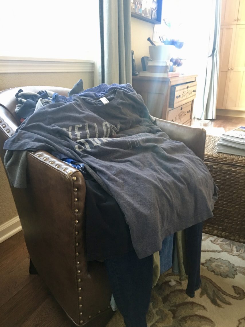 A t-shirt and jeans are laid out in a chair as if a person was inside them