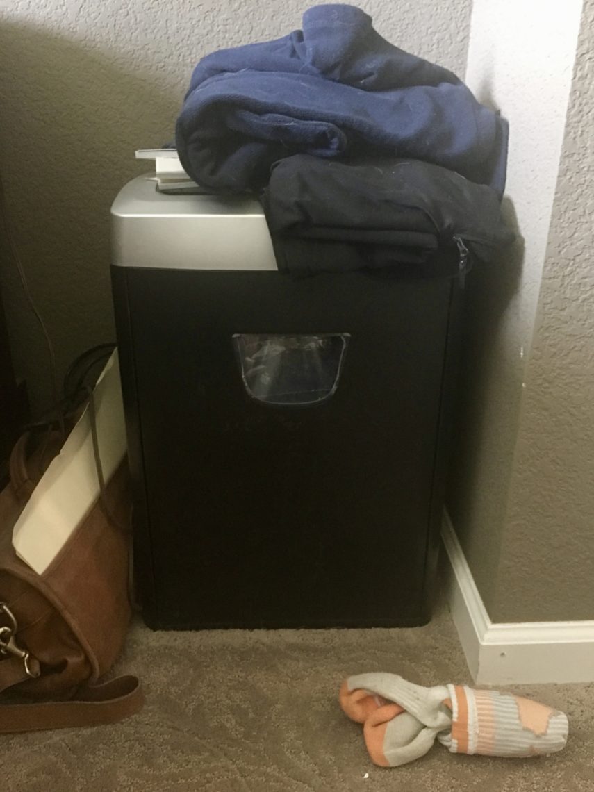 A pile of laundry rests atop a paper shredder