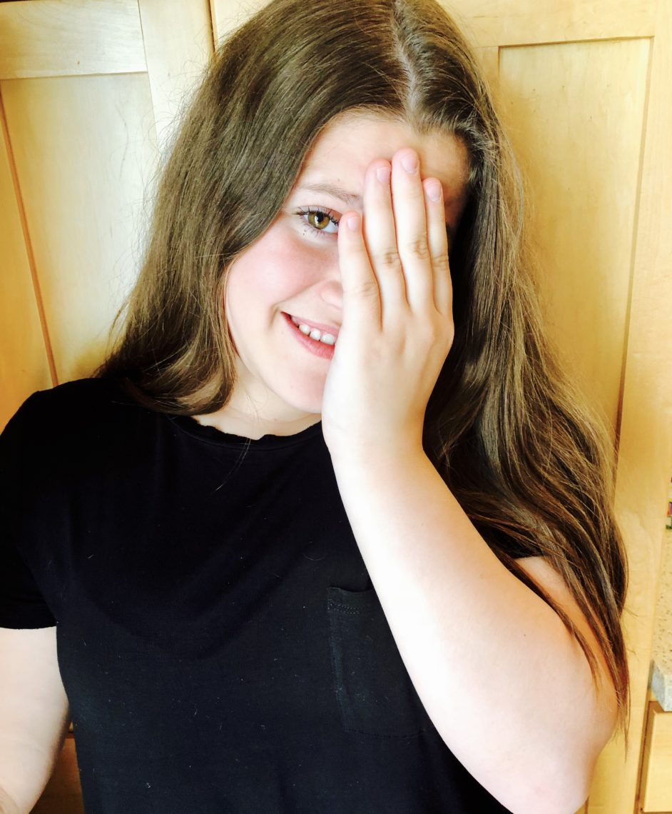 A picture of an embarrassed teenage girl shielding her eyes.
